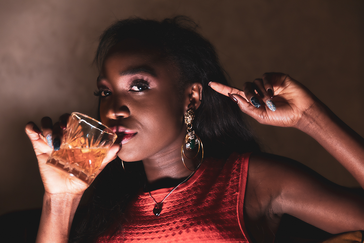 Frau hält ein Glas und zeigt mit dem Finger auf sich