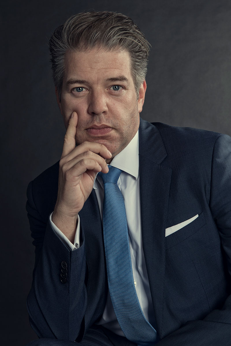 Mann im Anzug stützt seinen Kopf mit der rechten Hand.